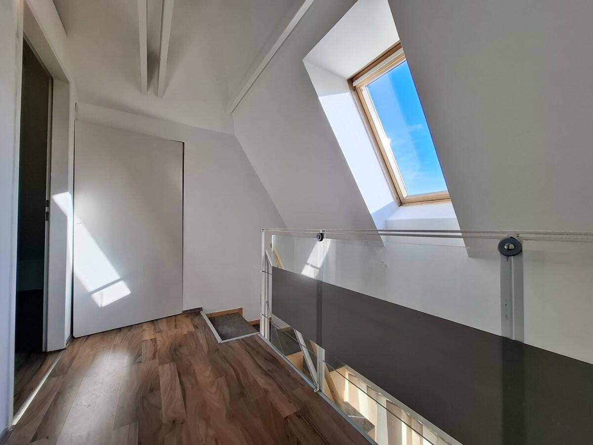 Dachgeschossraum mit Holzboden, Dachschräge und einem großen Dachfenster für viel Tageslicht.