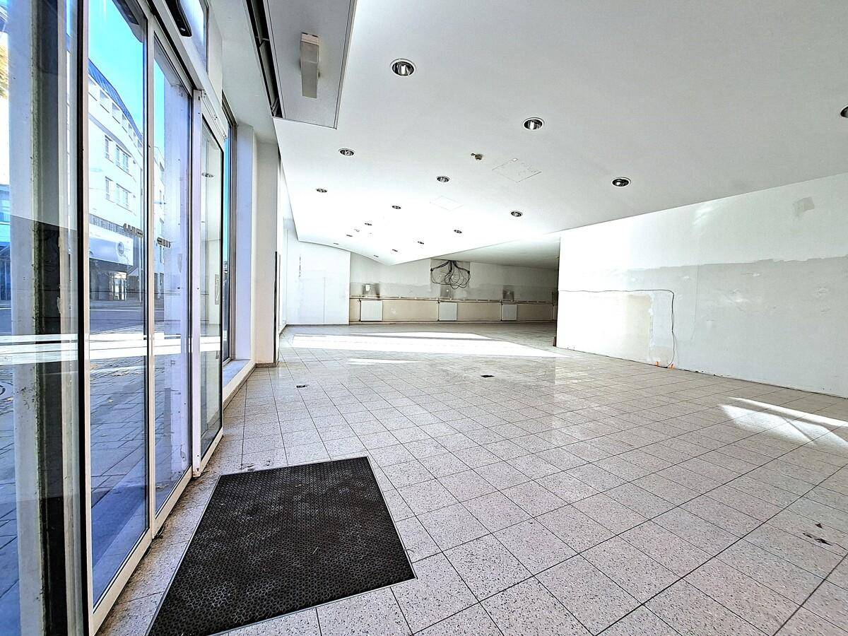 Geräumiger Gewerberaum mit großen Fensterfronten und Fliesenboden, ideal für Ladenlokal.