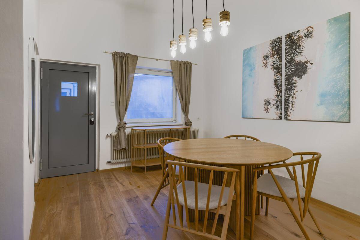 Essbereich mit Holztisch, Stühlen und Parkettboden, beleuchtet durch eine moderne Hängelampe.