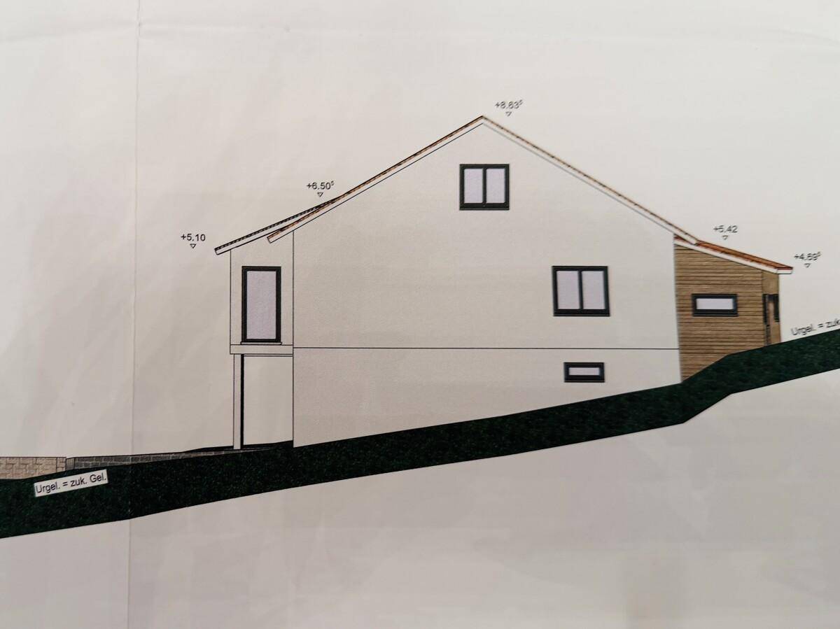 Seitenansicht des Hauses mit schrägen Dächern und modernen Fenstern.