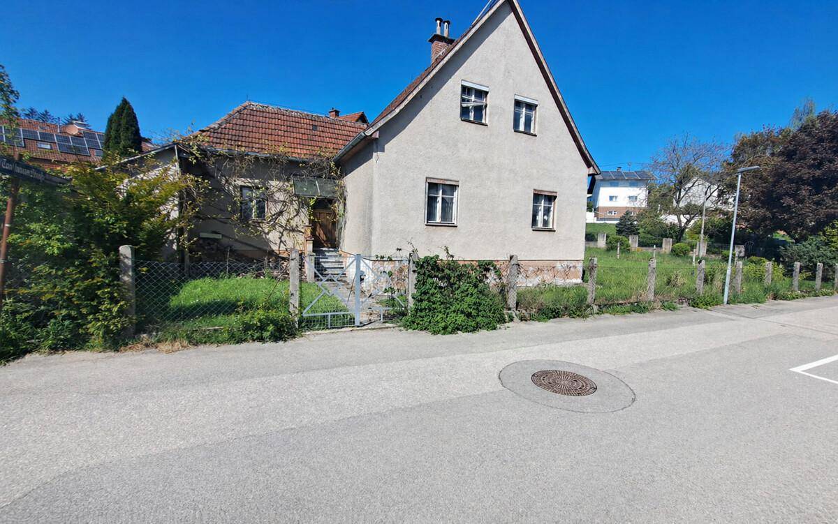 Ansicht des Einfamilienhauses von der Straße mit Vorgarten und Zaun.