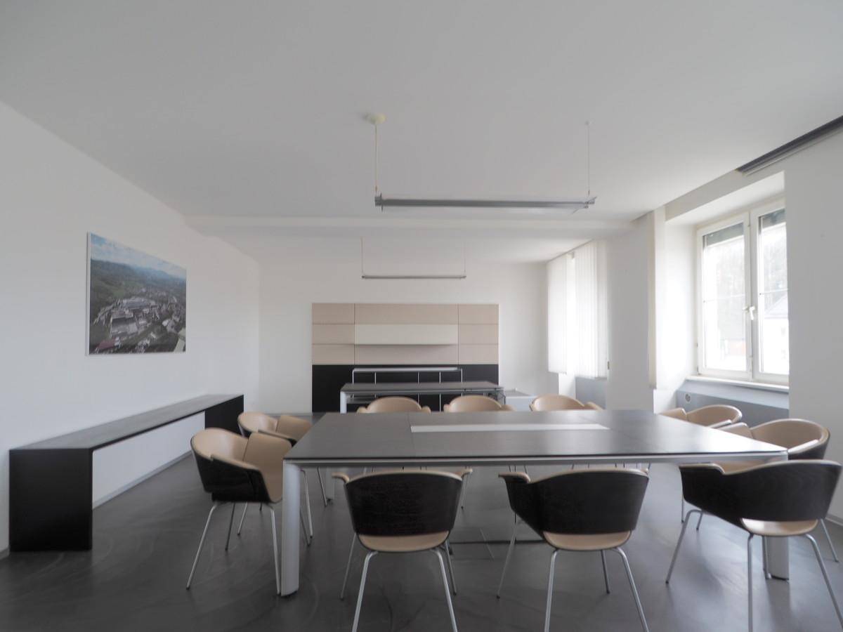 Moderner Konferenzraum mit großem Tisch, bequemen Stühlen und einem Sideboard an der Wand.