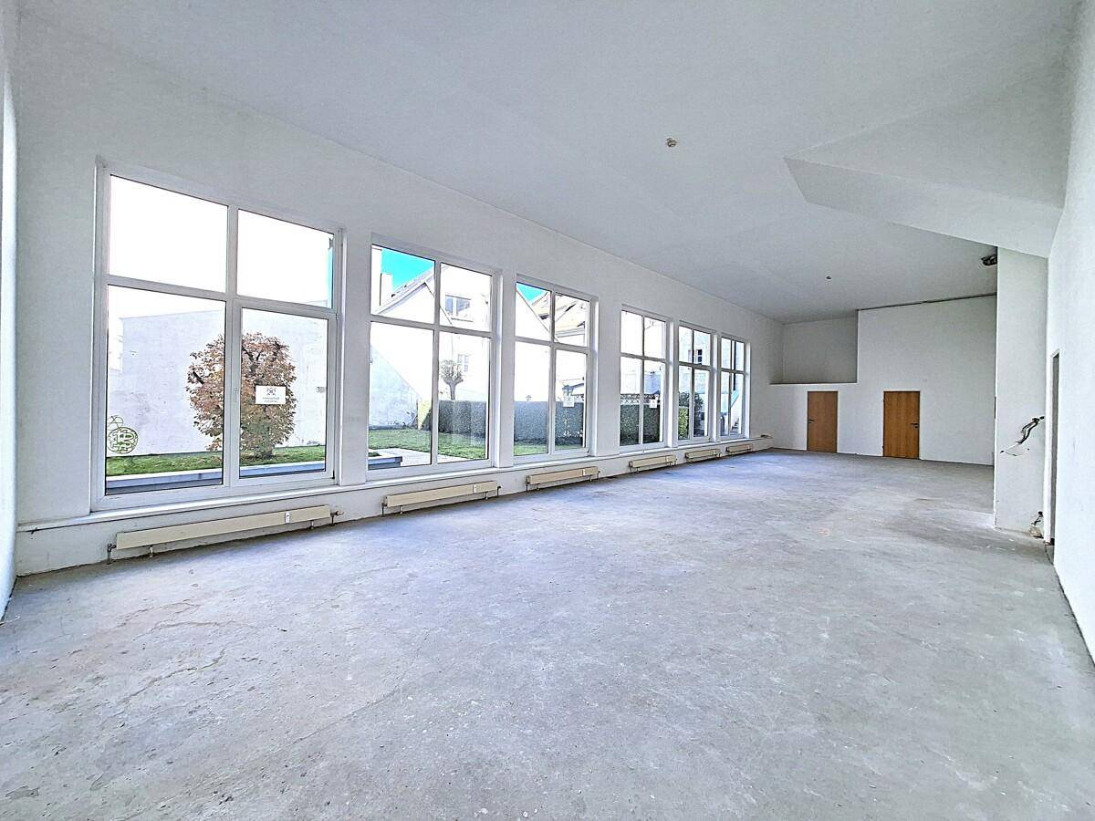 Heller und offener Gewerberaum mit durchgehenden Fenstern und Blick auf die Umgebung.