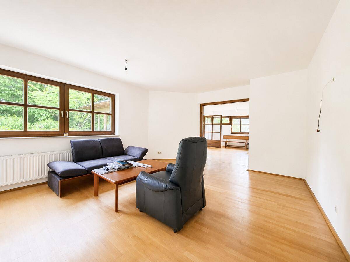 Helles Wohnzimmer mit Parkettboden und Blick in den angrenzenden Wintergarten.