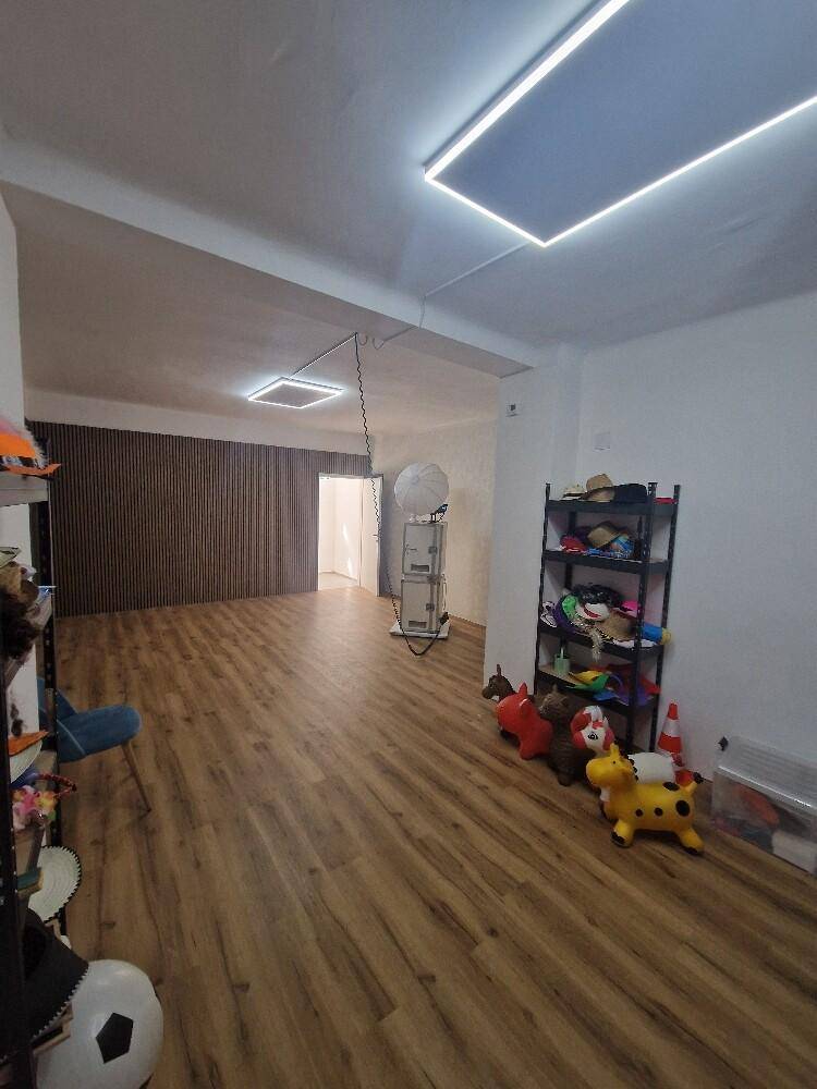Großer, offener Raum mit Holzboden und modernen Deckenleuchten, vielseitig nutzbar.