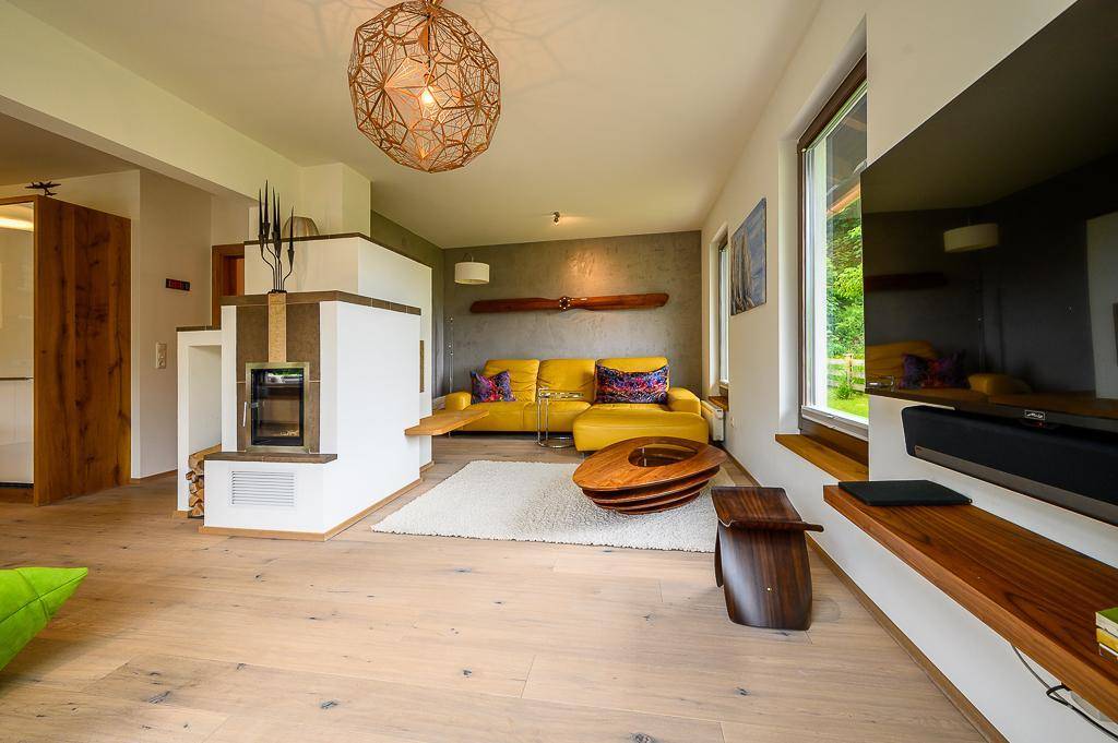 Gemütliches Wohnzimmer mit hellem Holzboden, Kamin und moderner Einrichtung.