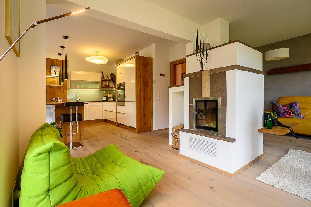 Heller Wohnbereich mit Kamin, Holzboden und offener Küche mit Bartresen.