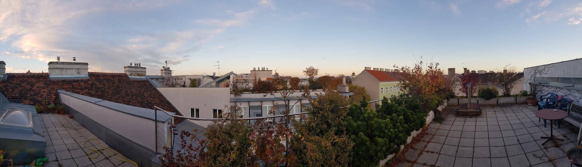 Weitläufige Dachterrasse mit Stadtblick und Sitzgelegenheiten unter weitem Himmel.