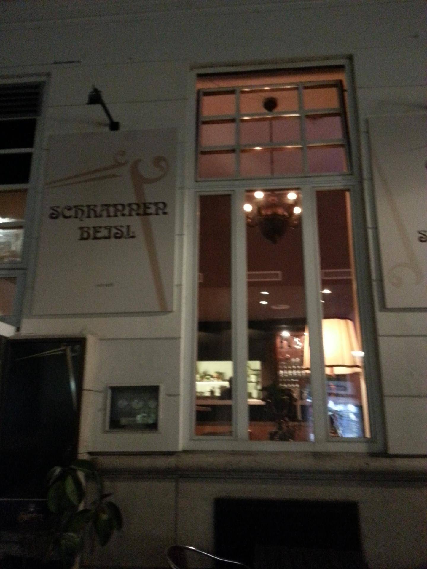 Fassade eines Gebäudes bei Nacht, mit einem beleuchteten Fenster, das Einblicke gewährt.
