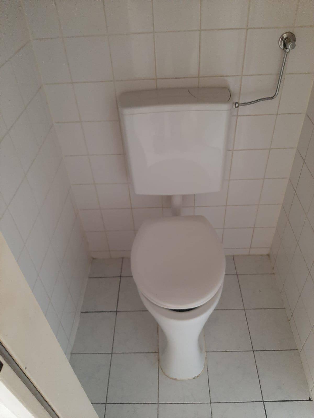 Separate Toilette mit weißem WC und hellen Wand- und Bodenfliesen, sauber und funktional.