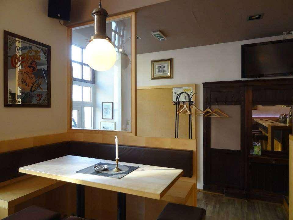 Gemütliche Sitzecke mit Holztisch, Fenster und dunklem Schrank in einem Café.