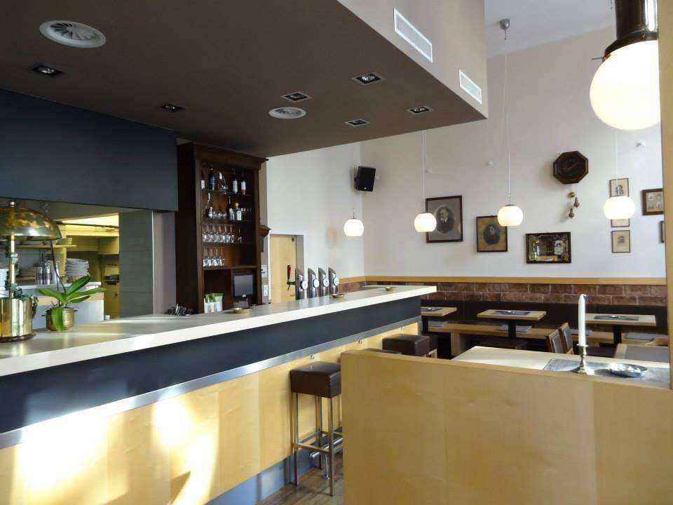 Moderne Bartheke mit Hockern und Blick in die professionelle Küche eines Gastronomiebetriebs.