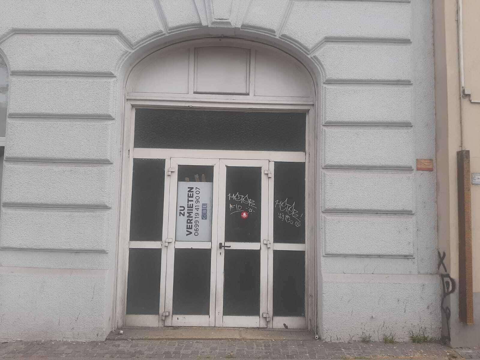 Nahaufnahme des Haupteingangs eines Gebäudes mit einer Doppeltür und einem Vermietungsschild.
