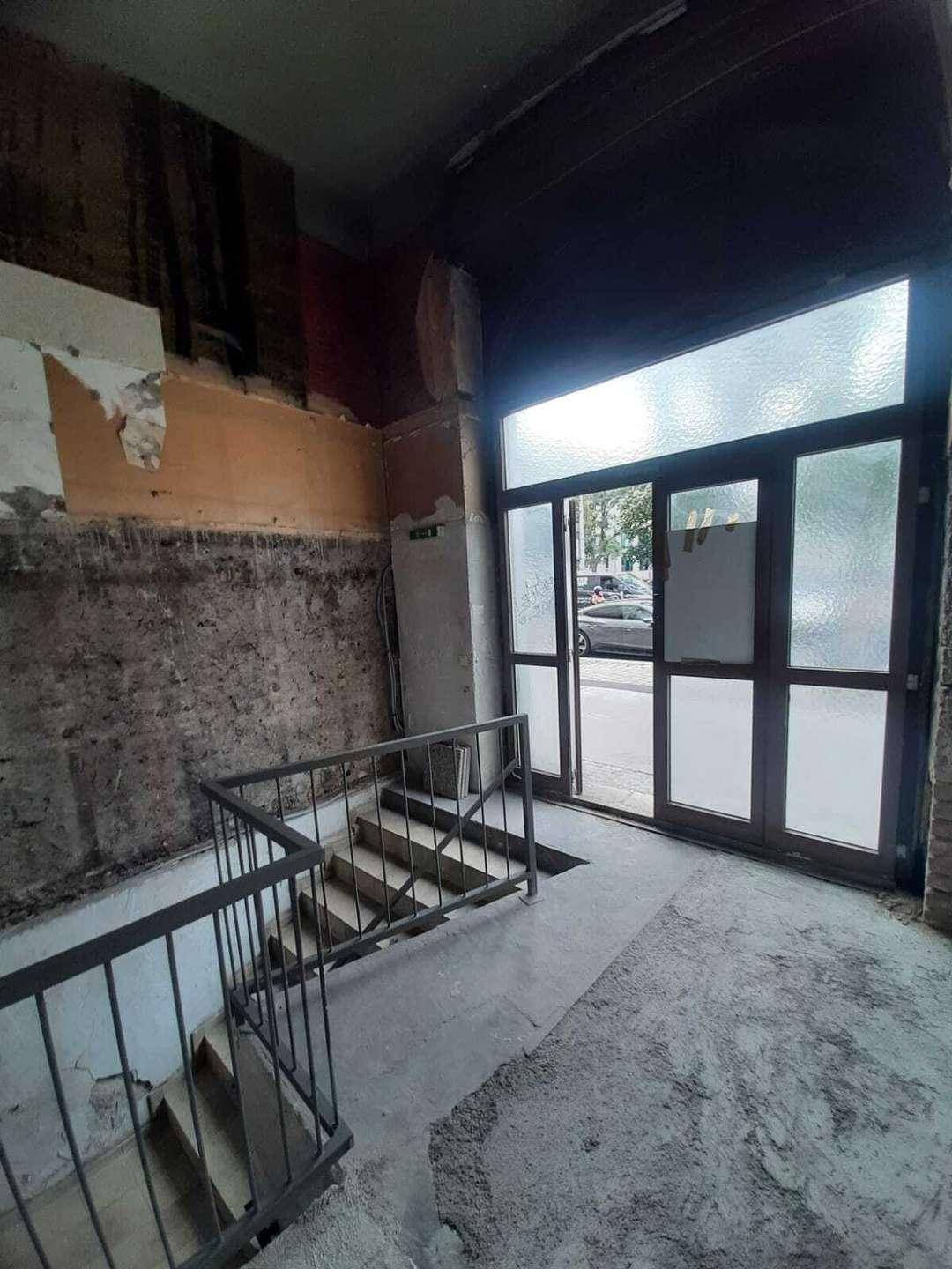 Eingangsbereich und Treppenhaus im Rohbauzustand mit viel Tageslicht durch die großen Türen.