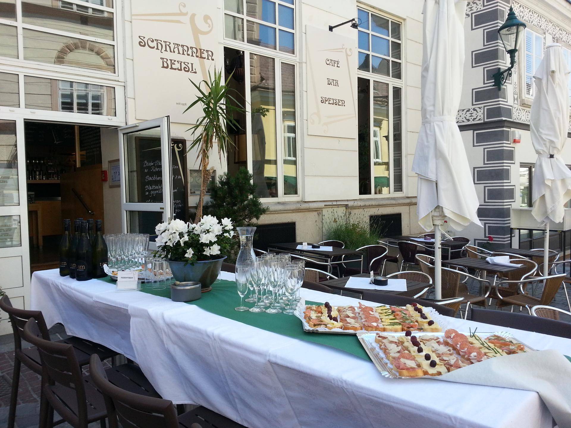 Außenbereich eines Cafés mit Tischen, Stühlen und einem Buffet, bereit für Gäste im Freien.