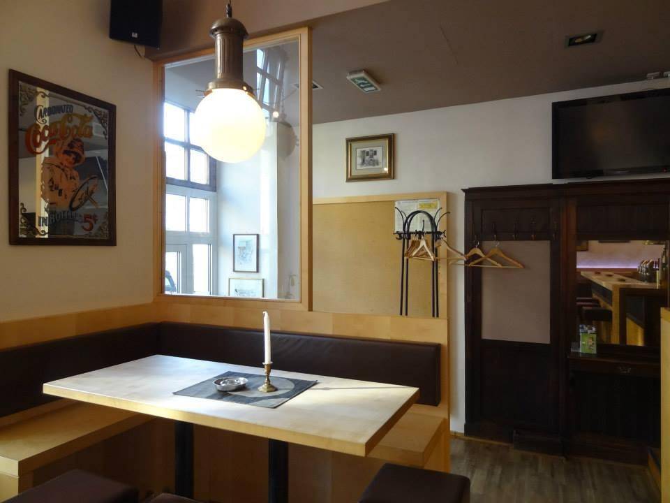 Gemütliche Sitzecke in einem Café mit Holztisch, gepolsterter Bank und Blick auf ein Fenster.
