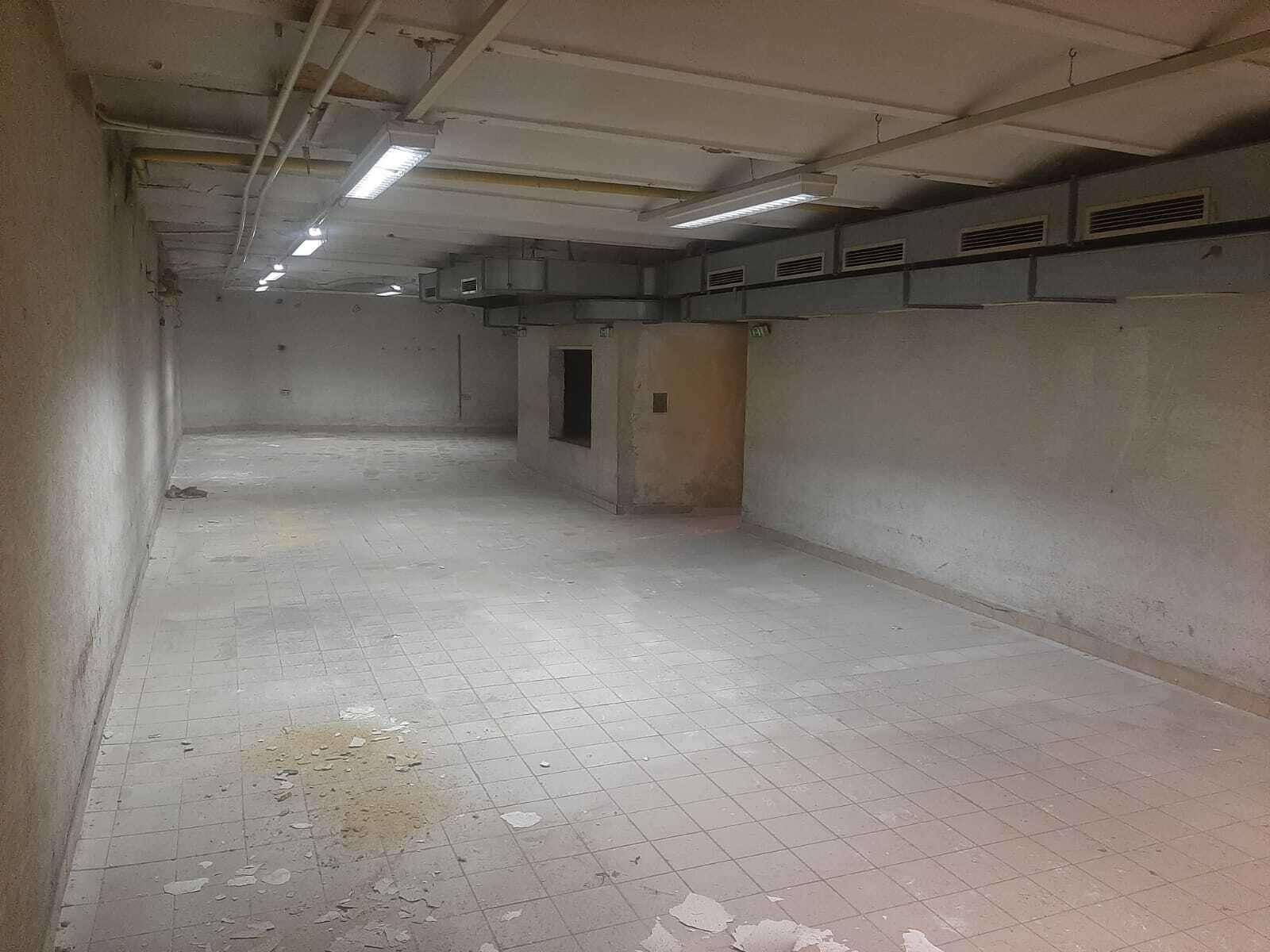 Weitläufiger, leerer Raum im Untergeschoss mit Fliesenboden und Deckenbeleuchtung.
