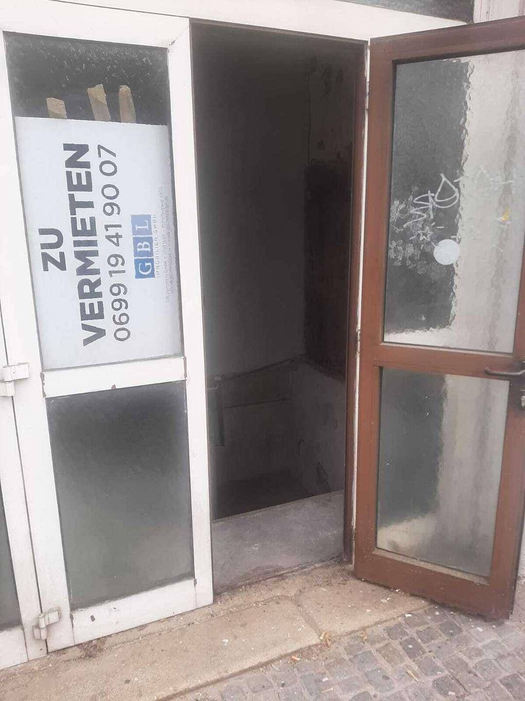 Blick durch die offene Eingangstür in einen dunklen Flur mit einem Vermietungsschild.