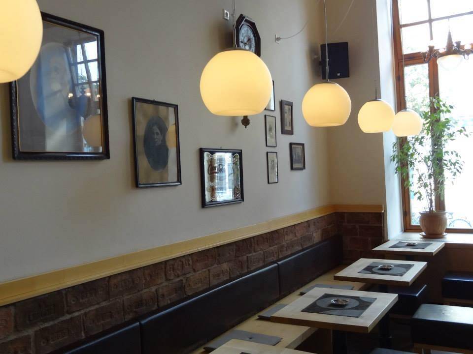 Detailansicht der Wanddekoration mit Bildern, Hängelampen und einer Ziegeloptik im unteren Bereich.