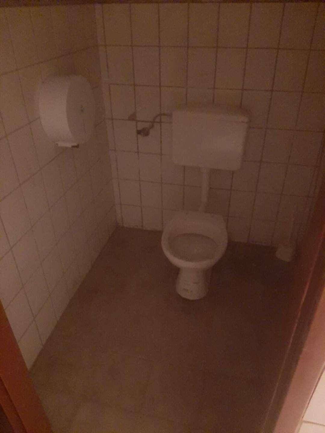 Kleiner Toilettenraum mit WC und weißen Wandfliesen, in einfachem Zustand.