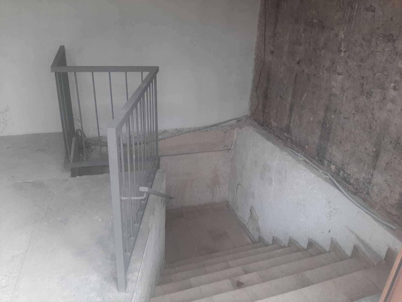 Treppenabgang in ein Untergeschoss oder einen Keller mit einfachem Metallgeländer.