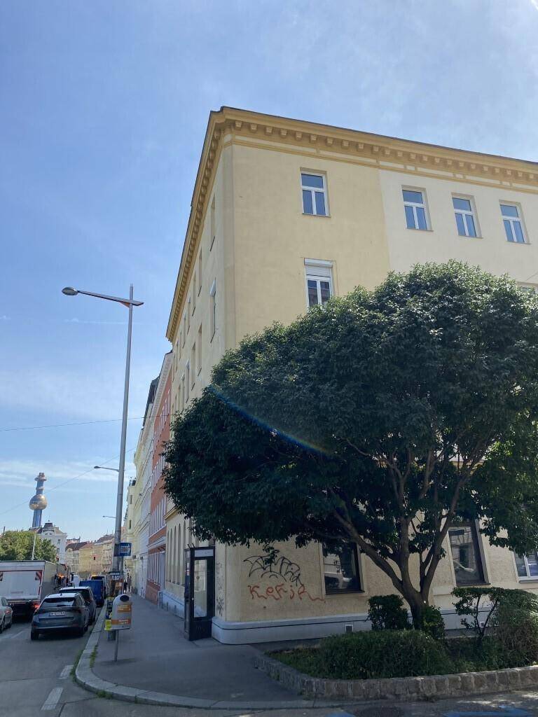 Historisches Gebäude mit gelber Fassade und vielen Fenstern an einer belebten Straße.