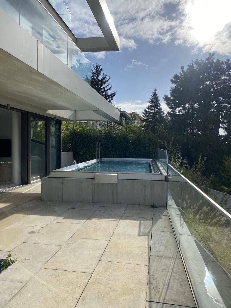 Geräumige Terrasse mit Pool und direktem Zugang zu den Innenräumen durch große Glasschiebetüren.