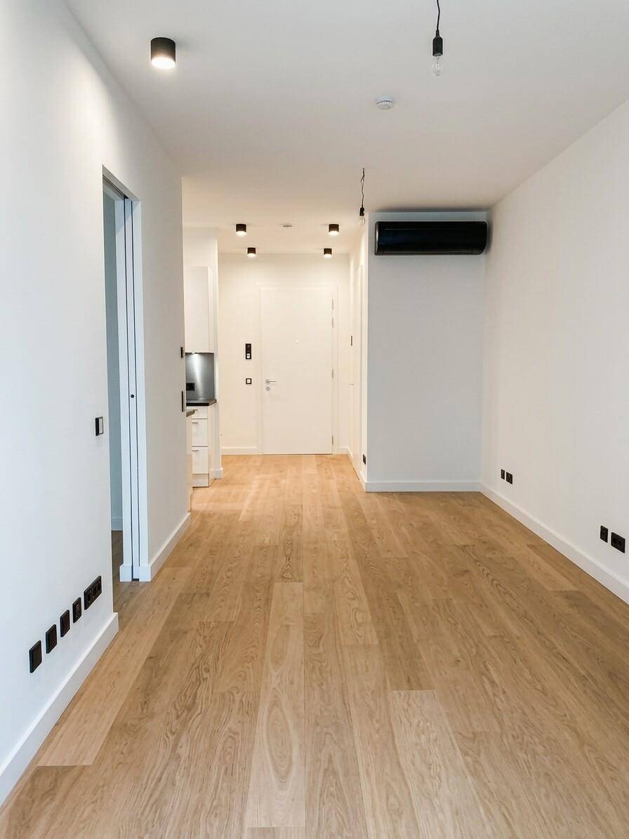 Heller Wohnbereich mit Holzboden, Klimaanlage und modernem Design, führt zum Eingang.