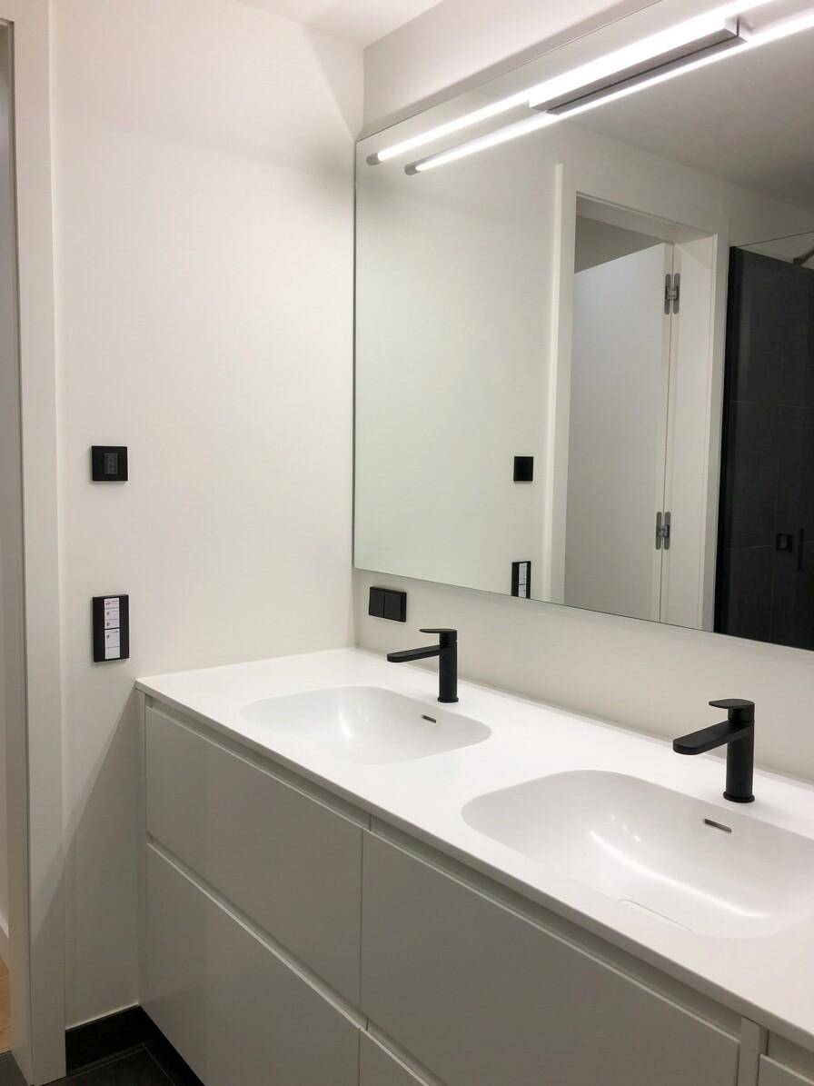 Modernes Badezimmer mit Doppelwaschbecken, großem Spiegel und stilvollen schwarzen Armaturen.