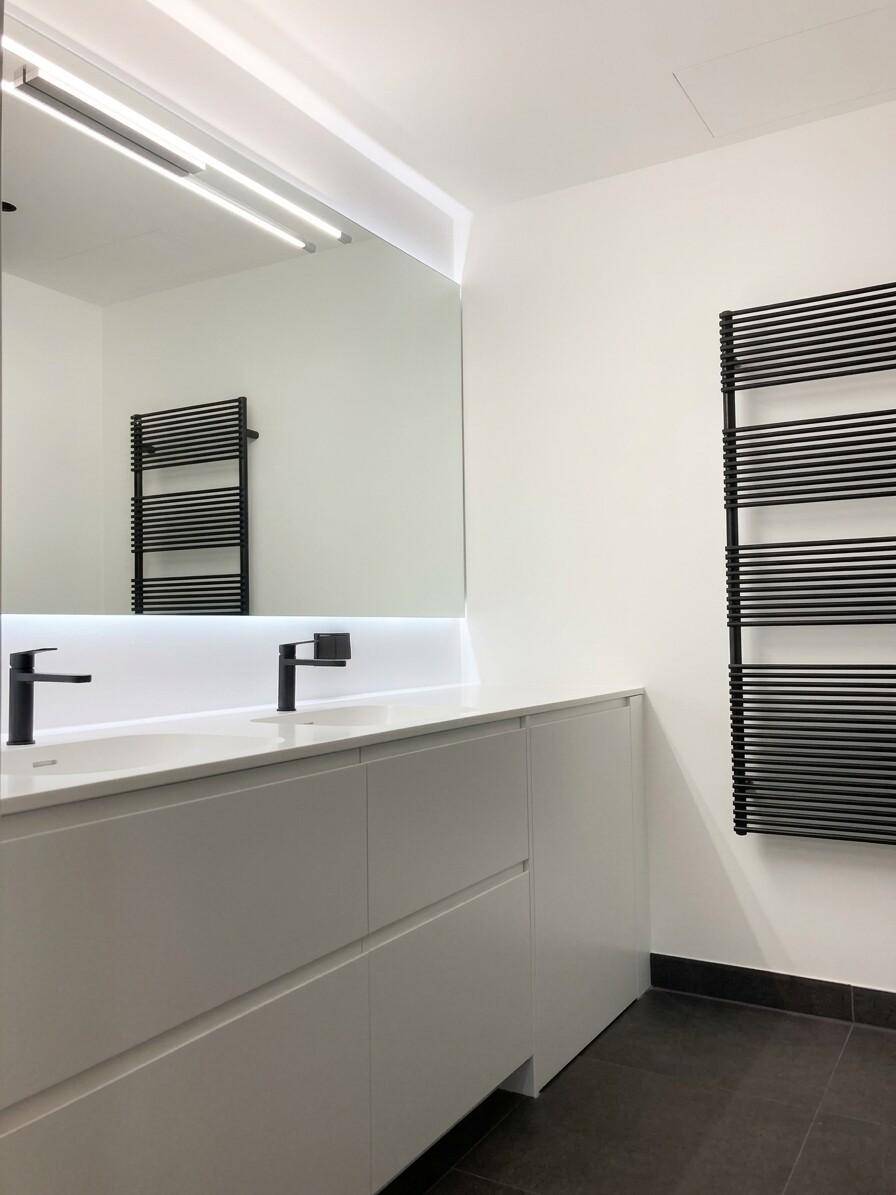 Modernes Badezimmer mit Doppelwaschbecken, großem Spiegel und beheiztem Handtuchhalter.