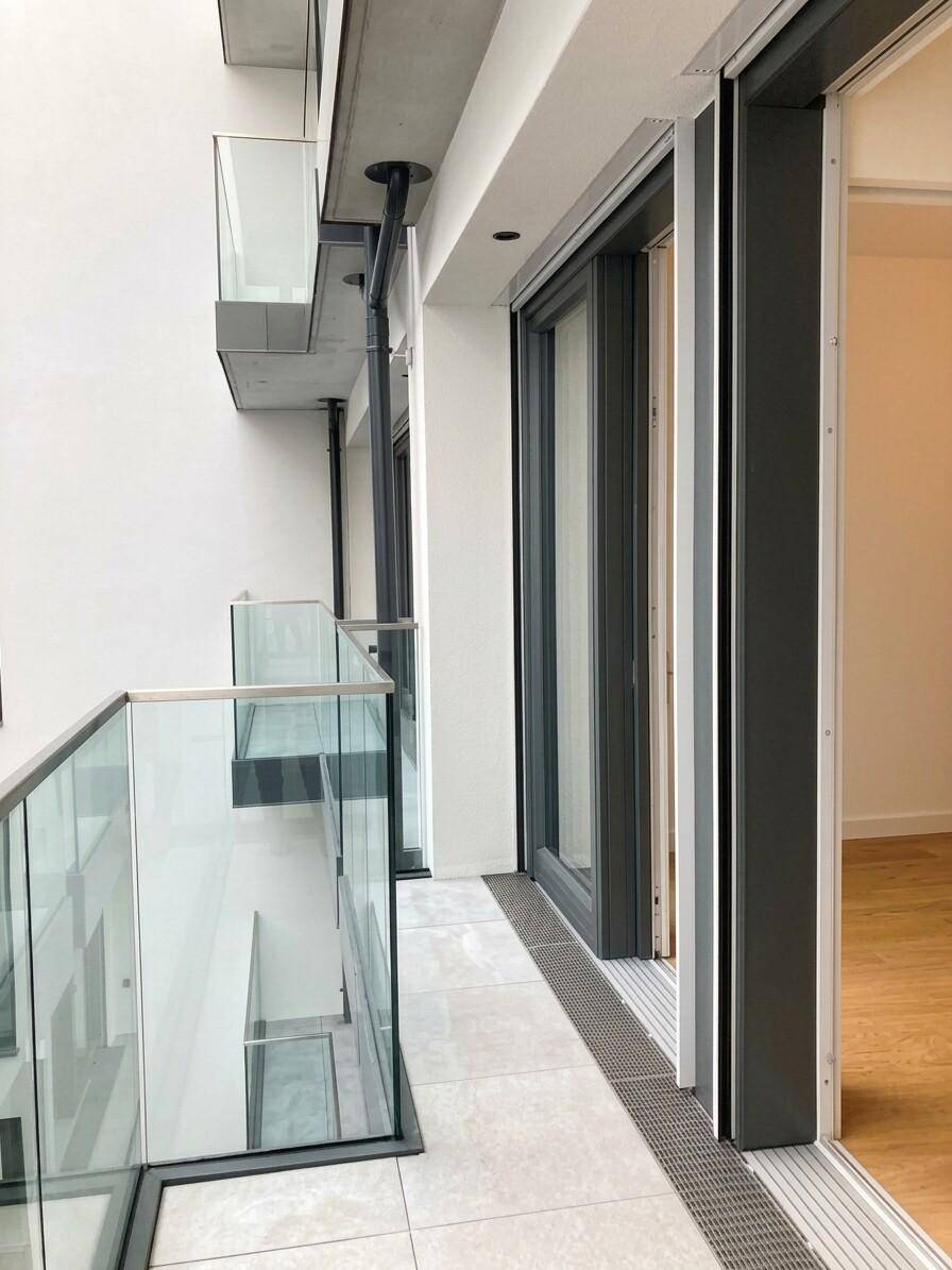 Schmaler Balkon mit modernem Glasgeländer und Zugang zum Innenbereich der Wohnung.