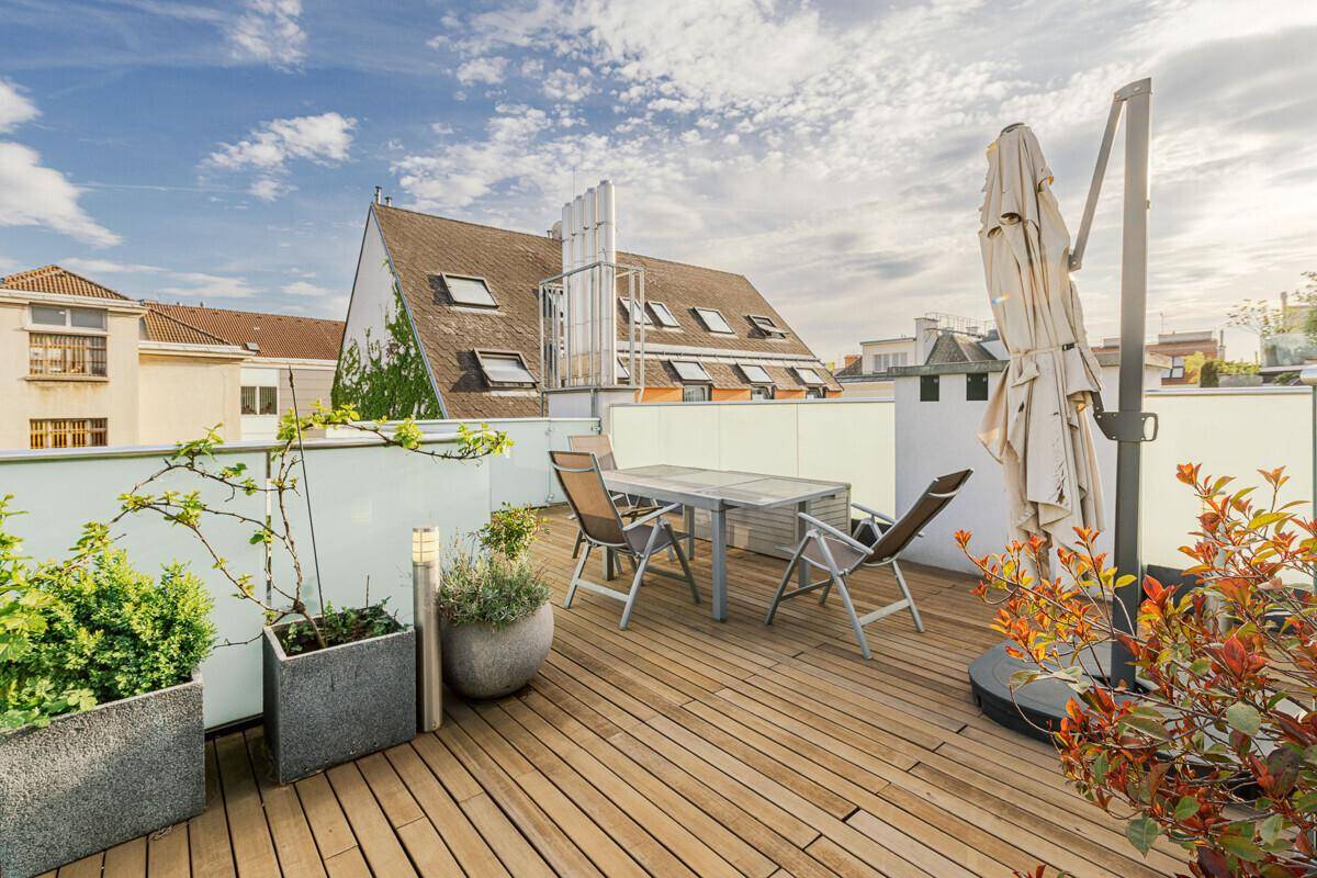 Helle Dachterrasse mit Holzfußboden, bequemen Gartenmöbeln und grünen Pflanzen in Töpfen.