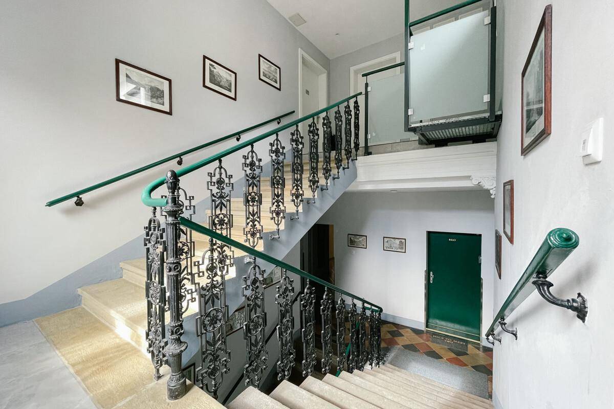 Prunkvolles Treppenhaus in einem Altbau mit schmiedeeisernem Geländer und integriertem Lift.
