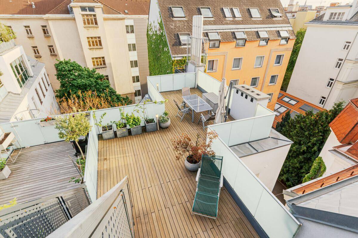 Geräumige Dachterrasse mit Holzdeck, Sitzgelegenheiten und weitem Blick über die Stadt.