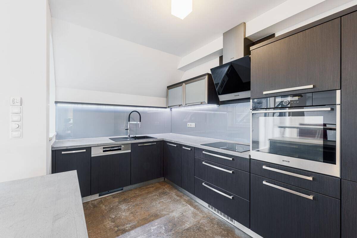 Dunkle, moderne Einbauküche mit integrierten Geräten, Induktionskochfeld und Dunstabzugshaube.