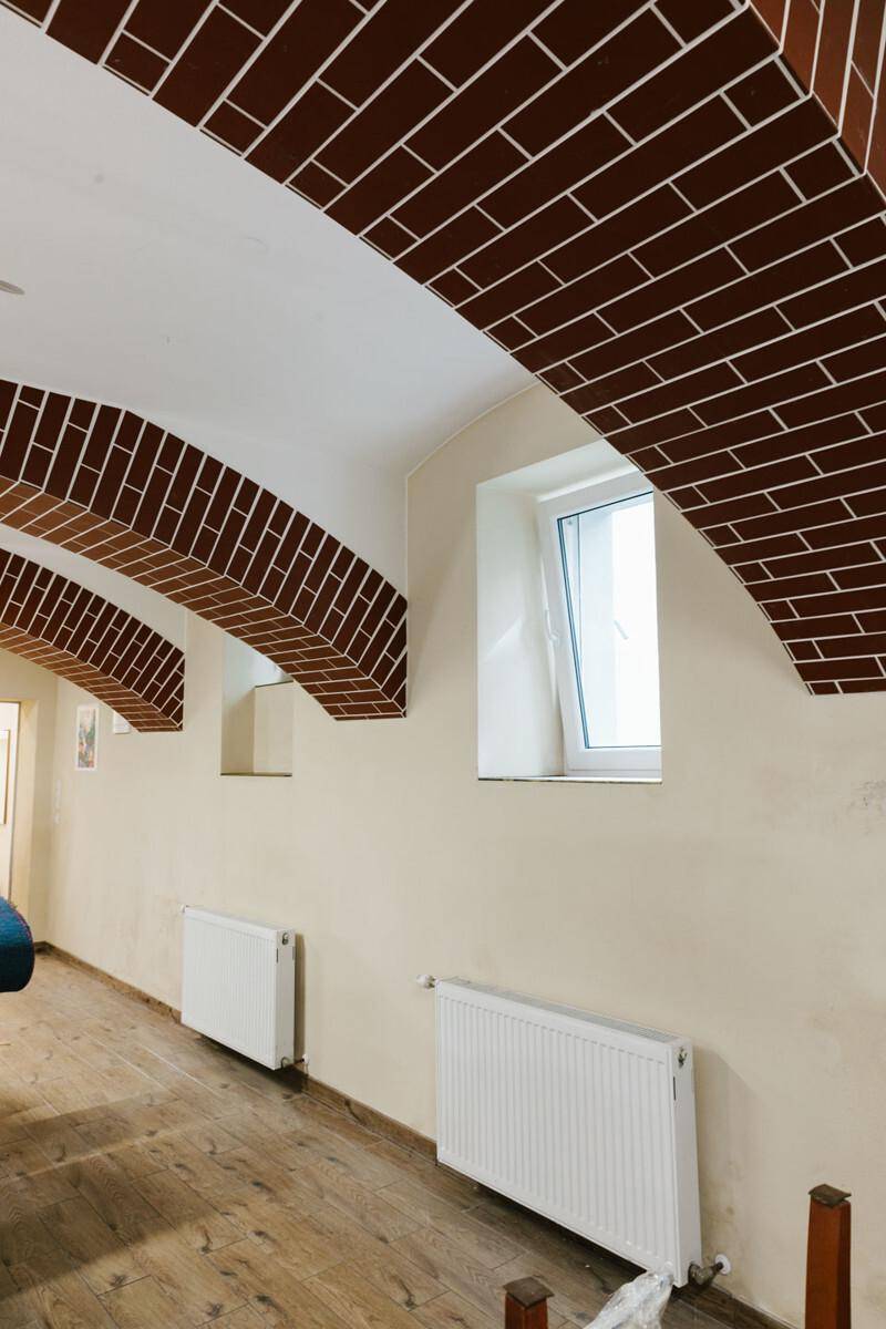Kellerraum mit charmanten Ziegelgewölben, Holzboden und Fenster für natürliche Belüftung.