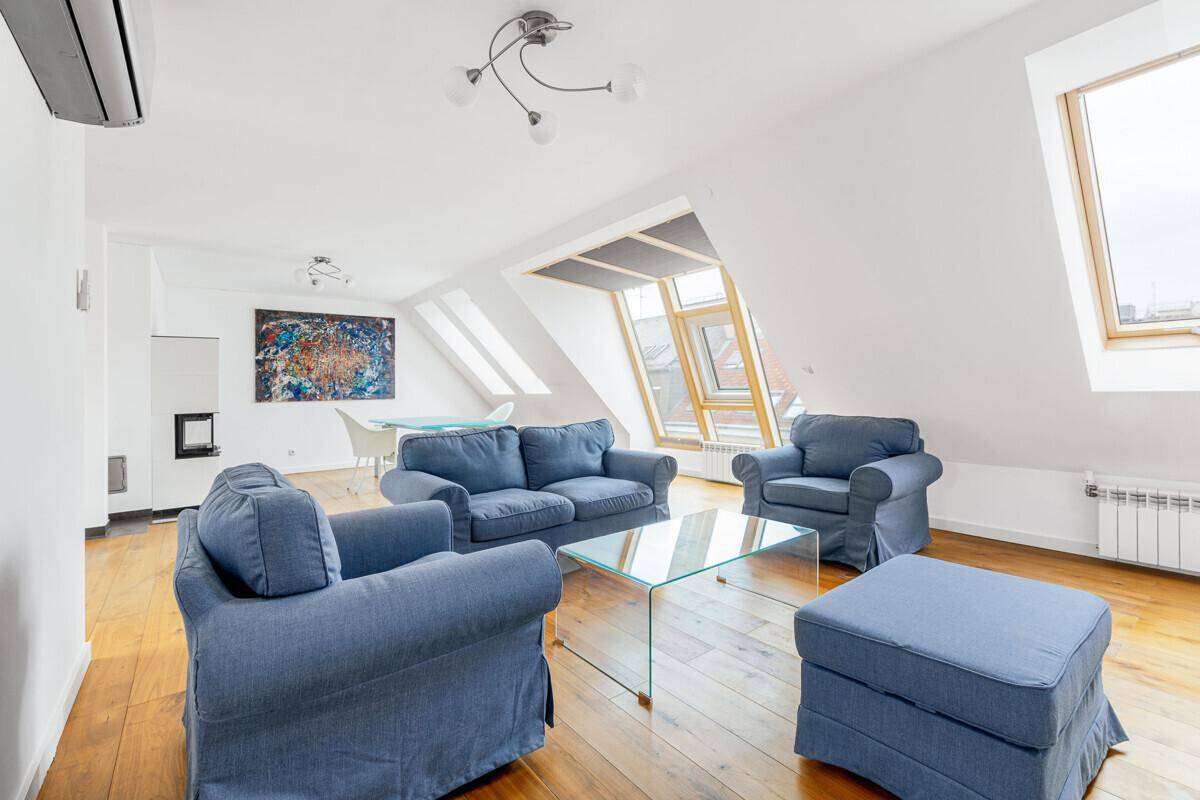 Gemütliches Wohnzimmer mit blauen Sofas, Glastisch, Klimaanlage und hellen Dachfenstern.