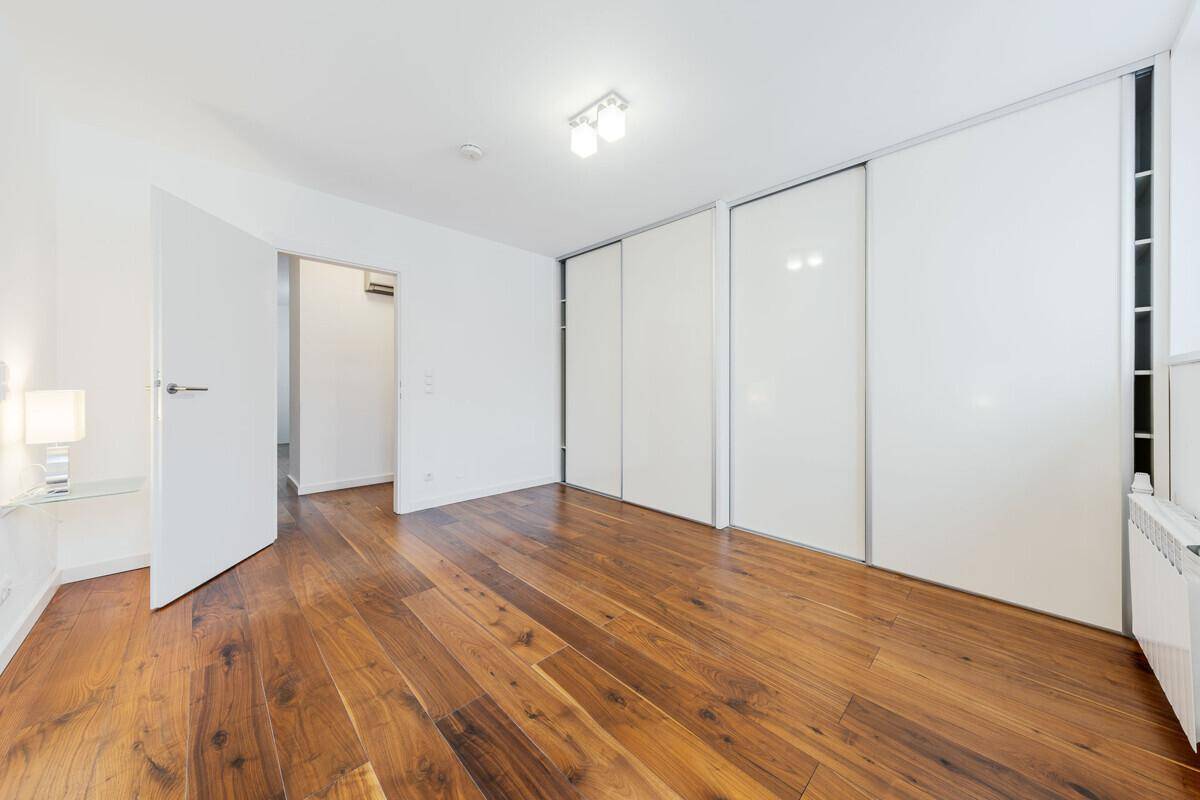 Helles Schlafzimmer mit elegantem Holzboden und praktischen Einbauschränken für viel Stauraum.