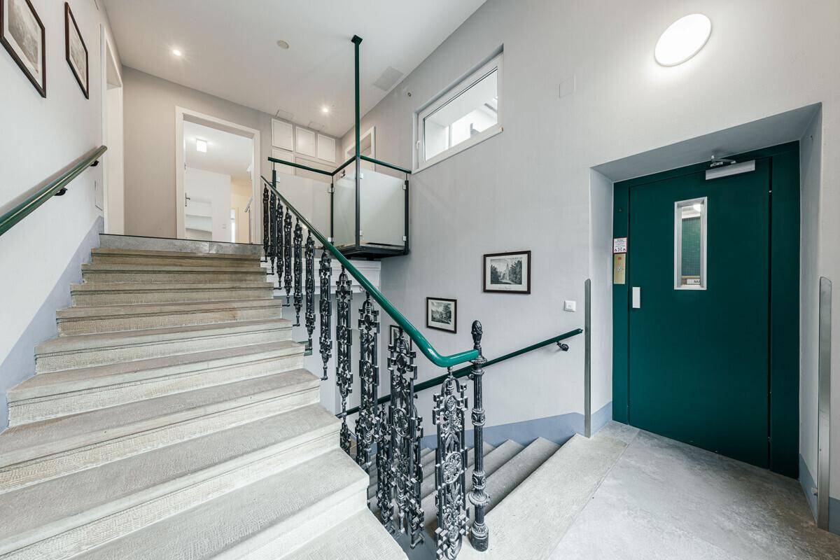 Historisches Treppenhaus mit kunstvollem Geländer und modernem Plattformlift für Barrierefreiheit.