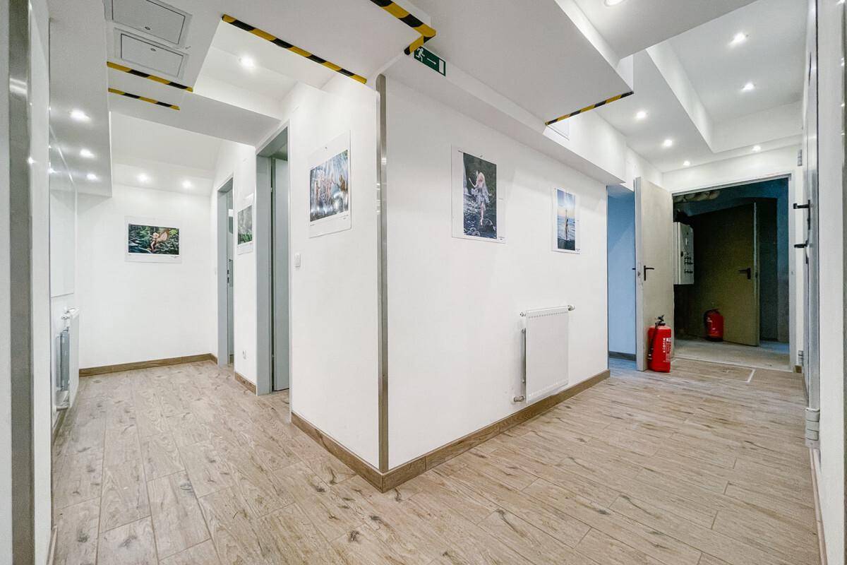 Heller Flur mit Fliesenboden in Holzoptik und klaren Notausgangsbeschilderungen.