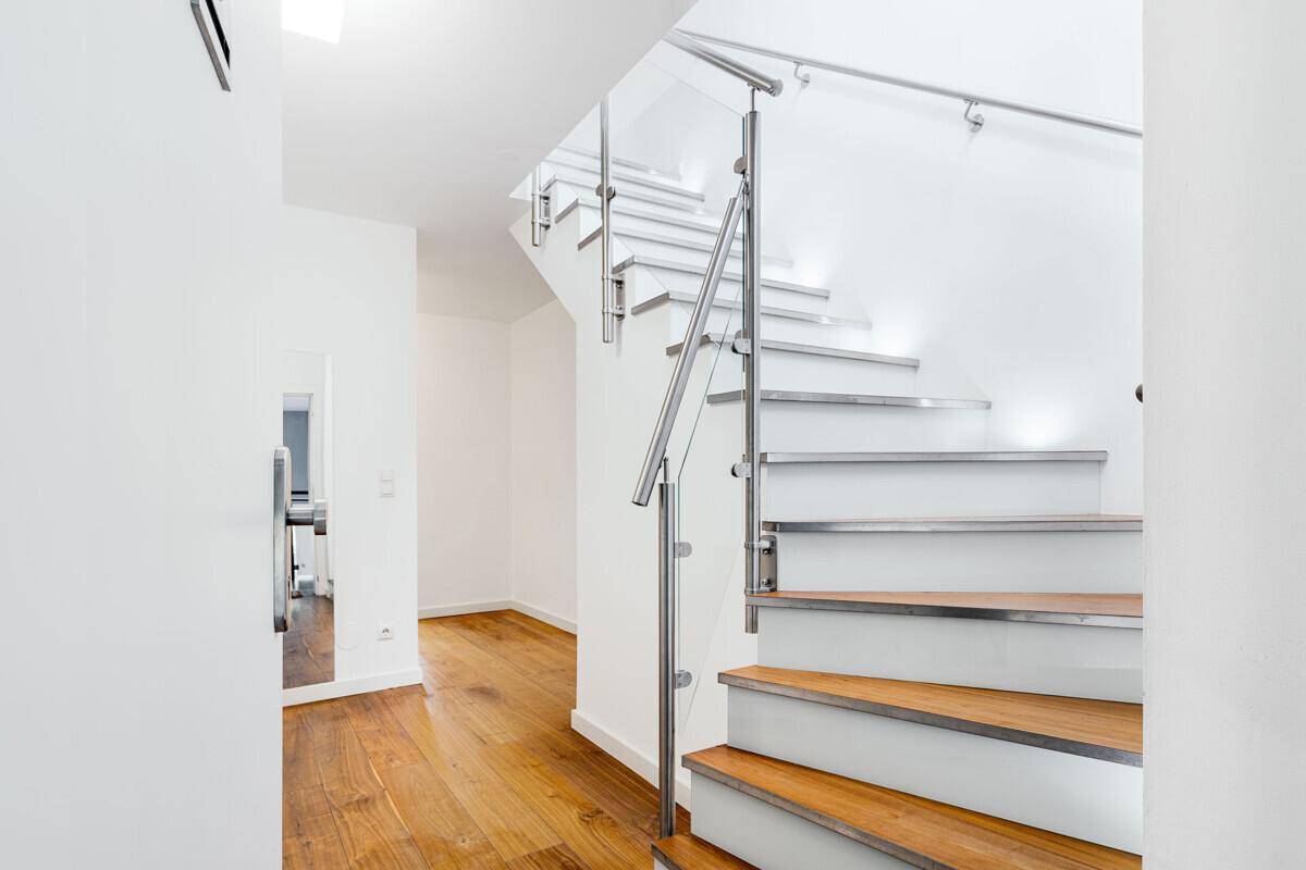 Moderne Treppe mit Holzstufen und Glasgeländer, die die verschiedenen Ebenen des Apartments verbindet.