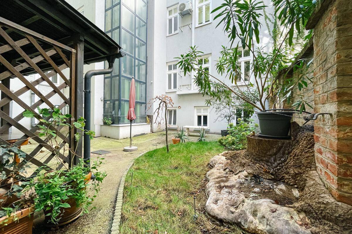 Ruhiger Innenhofgarten mit Rasenfläche, Pflanzen und einem charmanten Holzpavillon.