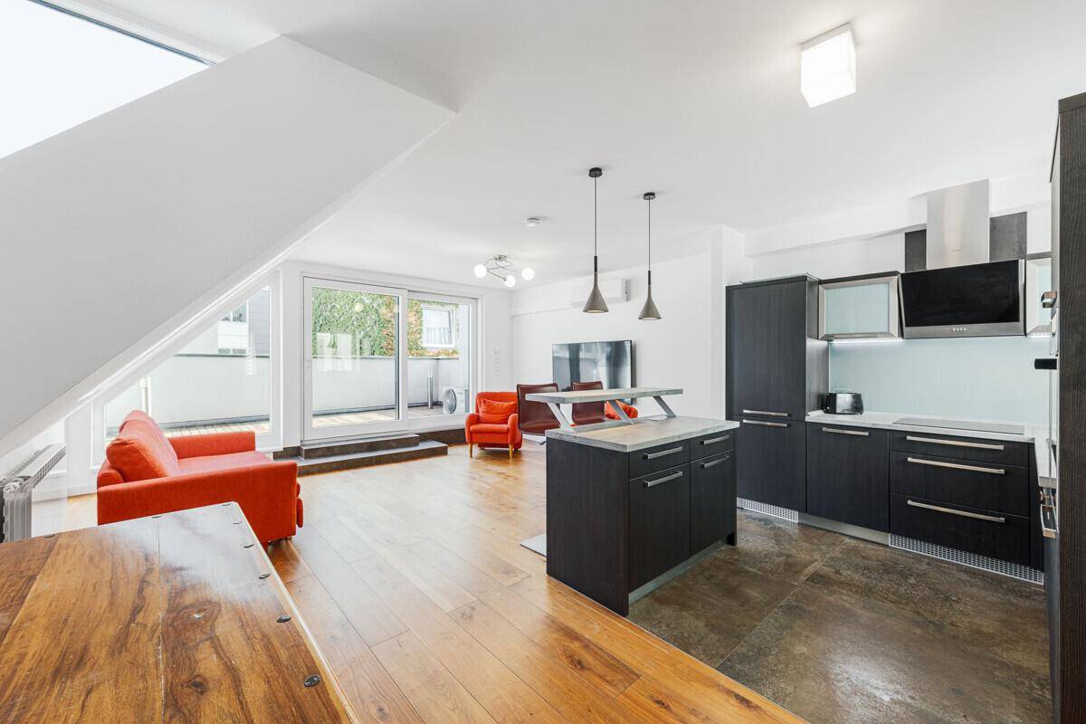 Offener Wohn-Essbereich mit moderner Küche, roten Sofas und Zugang zu einem Balkon.