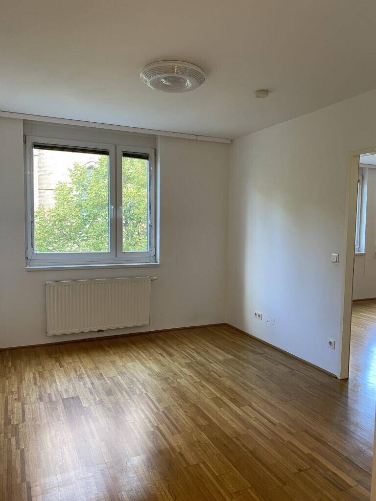 Gemütliches Zimmer mit Parkettboden und einem Fenster, das für ausreichend Tageslicht sorgt.