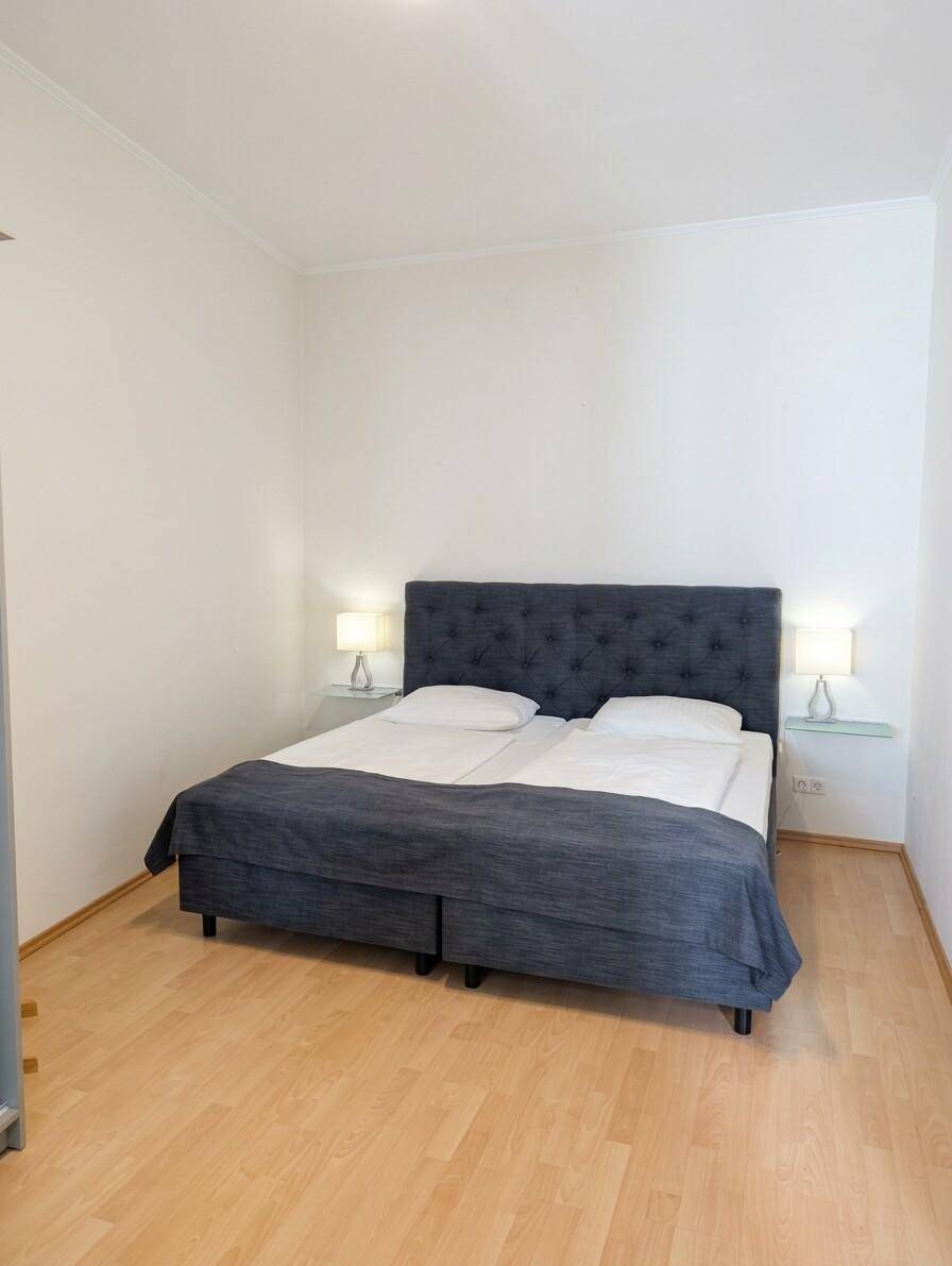 Schlafzimmer mit Doppelbett, Nachttischen und Lampen, sowie hellem Laminatboden.