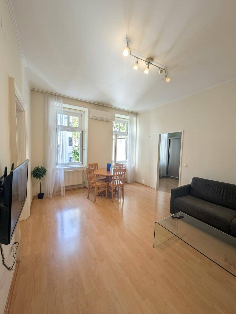 Offener Wohn-Essbereich mit Holzboden, Esstisch, Sofa und Fernseher.