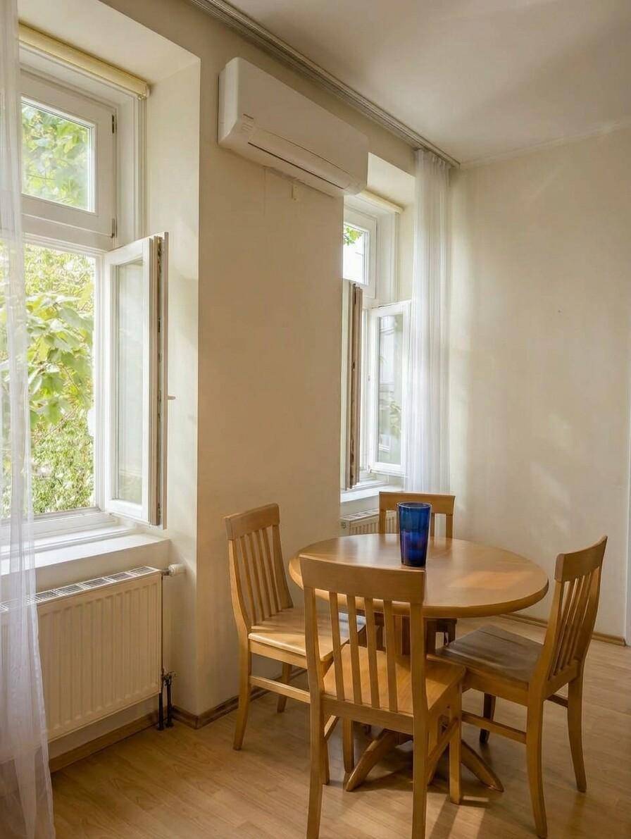 Heller Essbereich mit Holztisch und Stühlen, Klimaanlage und Blick ins Grüne.