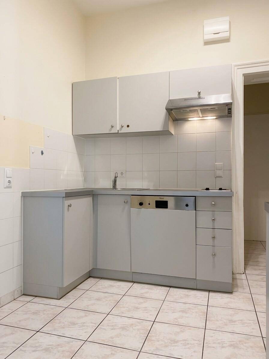 Helle Küche mit grauen Unterschränken, weißem Fliesenspiegel und integriertem Geschirrspüler.