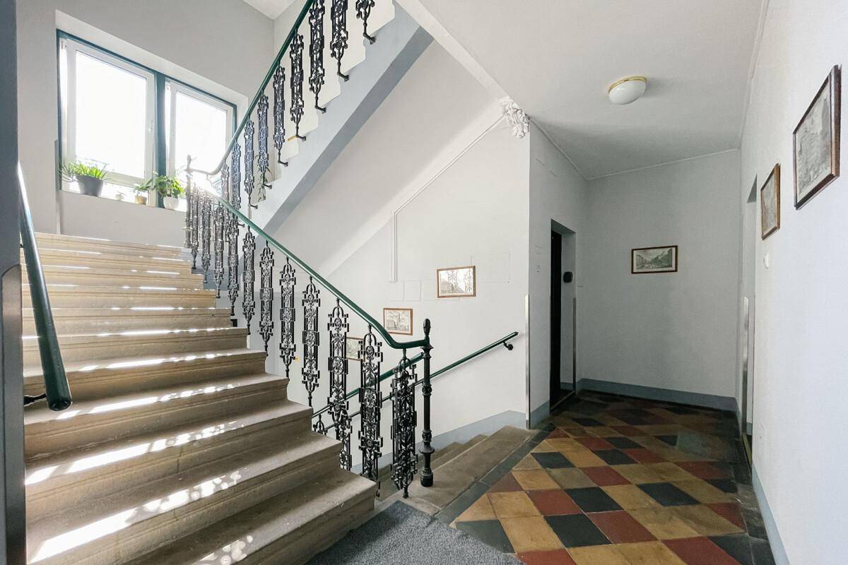 Historisches Treppenhaus mit kunstvollen Geländern und gemusterten Fliesen im Eingangsbereich.