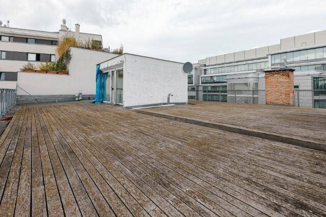 Weitläufige Dachterrasse mit Holzplanken und Blick auf die städtische Umgebung.